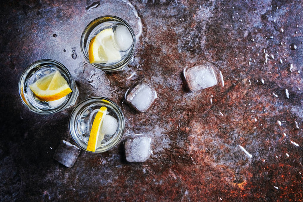 Vodka. Colpi, bicchieri con vodka con ghiaccio. Sfondo in pietra scura. Copia spazio. Focus selettivo
 - Foto, immagini