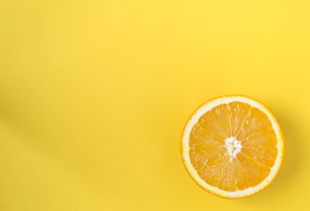 Half of orange isolated on a yellow background, top view - Foto, Imagen