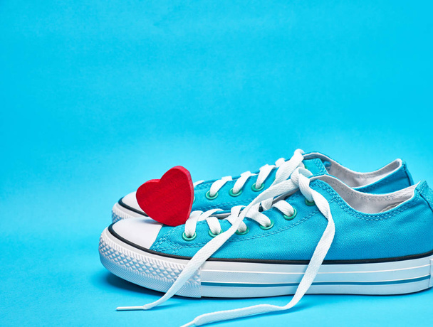 пара синіх текстильних кросівок з білими непокритими шнурками
  - Фото, зображення