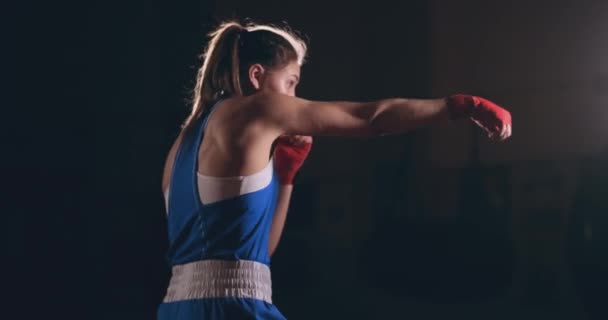 Die schöne Kämpferin in roten Binden führt während des Trainings im Fitnessstudio einen Schattenkampf. Zeitlupe. Steadicam-Aufnahme - Filmmaterial, Video