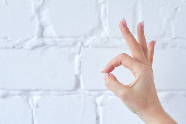 Hand gesture isolated on white brick wall background. - 写真・画像