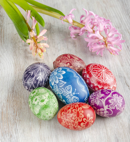 renkli Paskalya yumurtaları ve ahşap masaya pembe sümbül çiçek - Fotoğraf, Görsel
