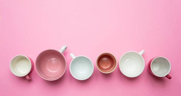 Lege koffie cups wit en roze kleur tegen roze achtergrond, bovenaanzicht - Foto, afbeelding