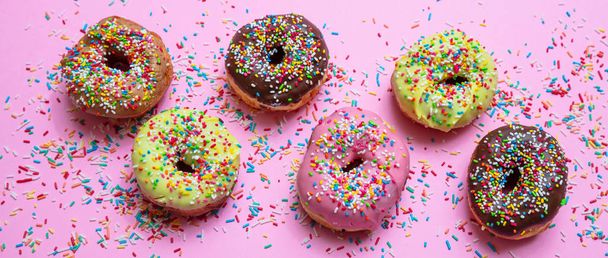 Donuts mit bunten Streuseln auf rosa Hintergrund, Draufsicht - Foto, Bild