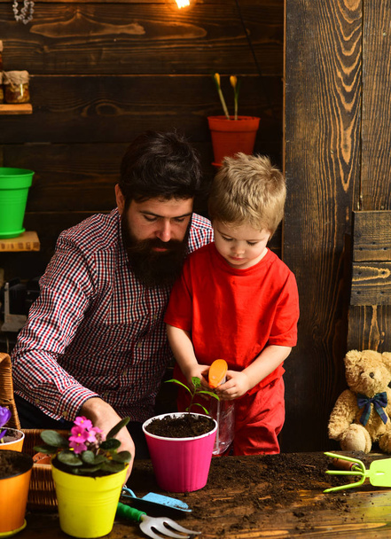 Flower care watering. Soil fertilizers. Father and son. Fathers day. Family day. Greenhouse. bearded man and little boy child love nature. happy gardeners with spring flowers. True professional - Foto, Imagen