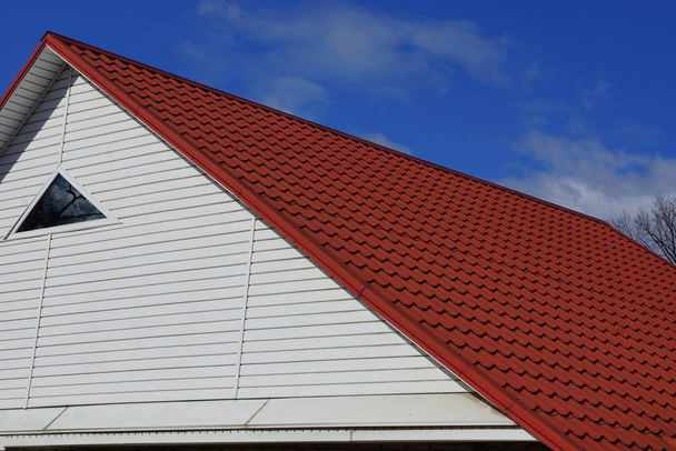 biały na poddaszu z małym okienkiem pod dachem czerwony dachówka przeciwko niebo i chmury - Zdjęcie, obraz