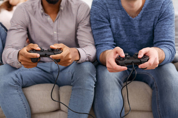 Мужчины играют в видеоигры по телевизору, держа в руках джойстики
 - Фото, изображение
