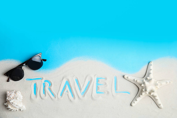 Flat lay composition with sand, sunglasses and word TRAVEL on color background, space for text. Tourist agency - 写真・画像