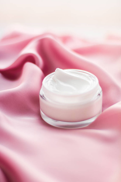 Frasco de crema facial de lujo sobre una suave seda rosa
 - Foto, imagen