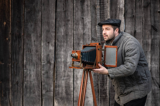 Ο παλιομοδίτης φωτογράφος δουλεύει με κάμερα μεγάλης μορφής. Concept-φωτογραφία της δεκαετίας του 1930-δεκαετία του 1950 - Φωτογραφία, εικόνα