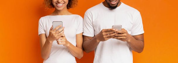 fröhliches schwarzes Millennial-Paar beim Surfen auf Mobiltelefonen - Foto, Bild