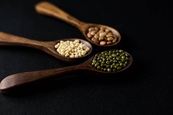 collection set of beans, green peas, lentils on wooden spoons isolated on wooden background.  - Fotó, kép