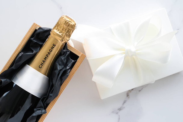 A champagne bottle and a gift box on marble - Photo, Image
