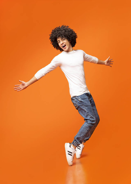 Jonge grappige Afrikaans-Amerikaanse man staande op zijn tenen - Foto, afbeelding