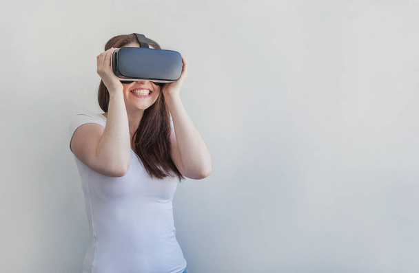 Sonríe mujer joven usando realidad virtual gafas VR casco auriculares sobre fondo blanco
 - Foto, imagen