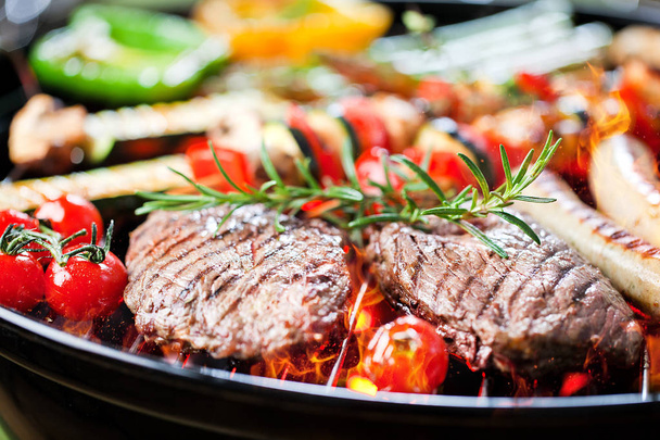 Close-up uitzicht op steaks, worstjes en groenten op grill  - Foto, afbeelding