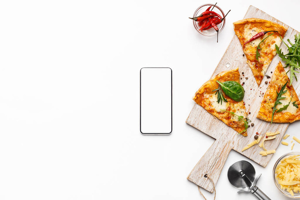 Pizza szelet, és a smartphone-val üres képernyő - Fotó, kép