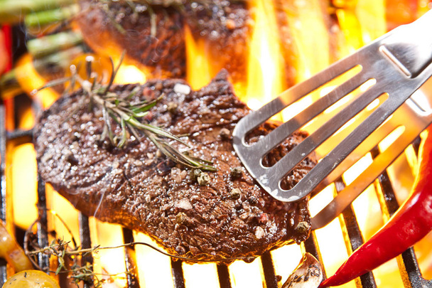 close-up view of delicious steaks with vegetables and rosemary cooking on grill  - Photo, Image