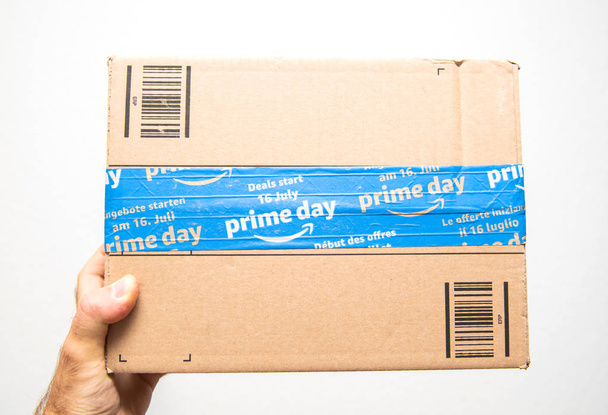 Man hand holding against white Amazon Prime Day cardboard box - Foto, afbeelding