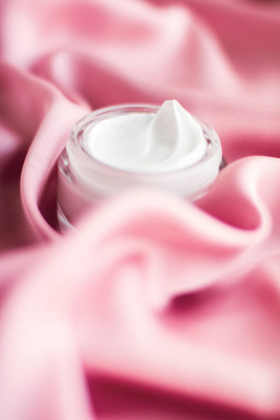 Роскошная банка крема для лица на мягком розовом шелке
 - Фото, изображение