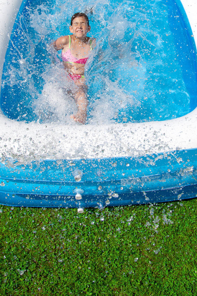 high angle view of cute happy teen girl playing in pool at summertime   - Foto, imagen