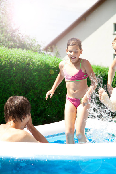 cute happy kids playing in the garden pool at summertime - Foto, Imagem