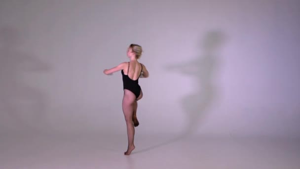 attraktives Mädchen dreht im Studio professionell Pirouette in Zeitlupe - Filmmaterial, Video