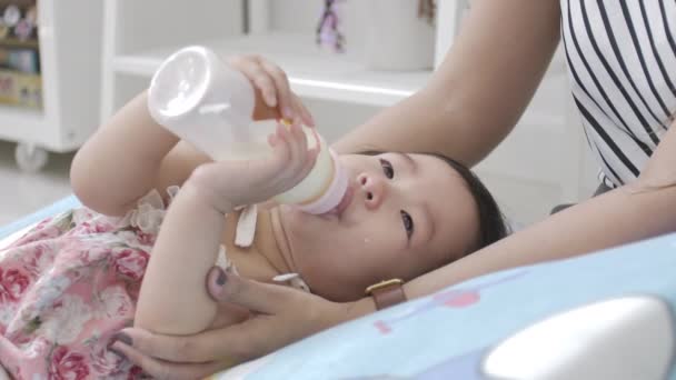 Bambino asiatico che beve latte da una bottiglia con genitore a casa. 4K rallentatore carino bambino è riposo
. - Filmati, video