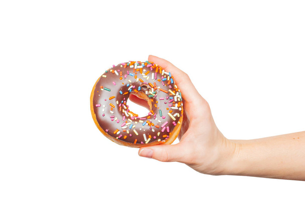 Female hand holding colorful donut on pastel white background - Foto, afbeelding