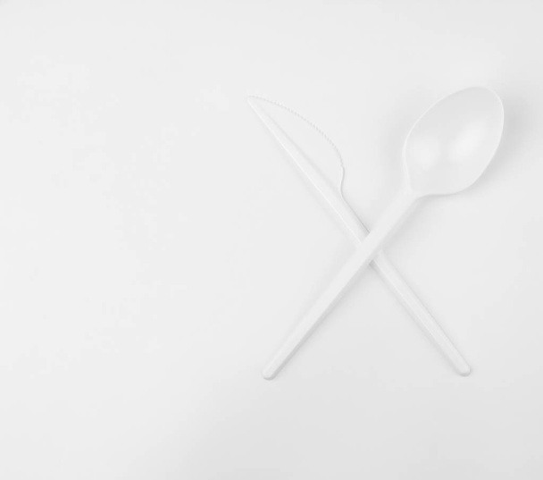 きれいな白いプラスチック白い背景の上のスプーンとナイフの交差  - 写真・画像