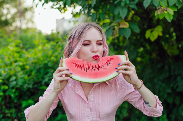 Beautiful young woman with pink hair enjoying watermelon - Foto, afbeelding