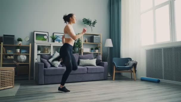 Good-looking girl student doing exercises at home running on the spot in flat. - Πλάνα, βίντεο