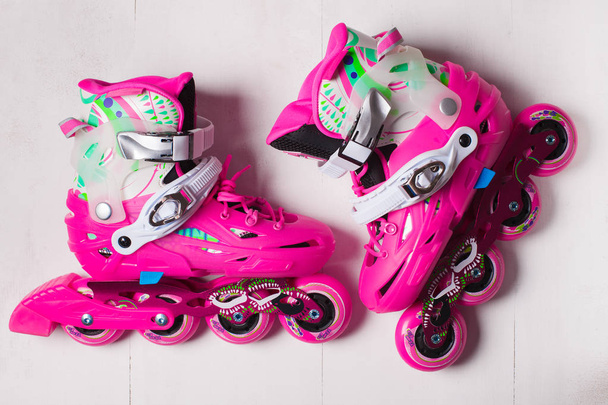 A pair of pink stylish roller skates on a white wooden background - Fotoğraf, Görsel