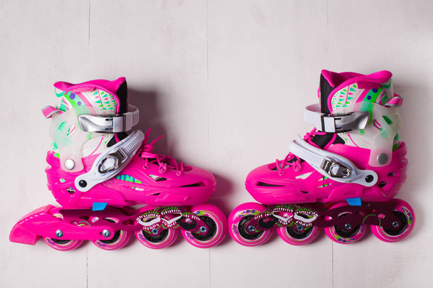 A pair of pink stylish roller skates on a white wooden background - Fotoğraf, Görsel