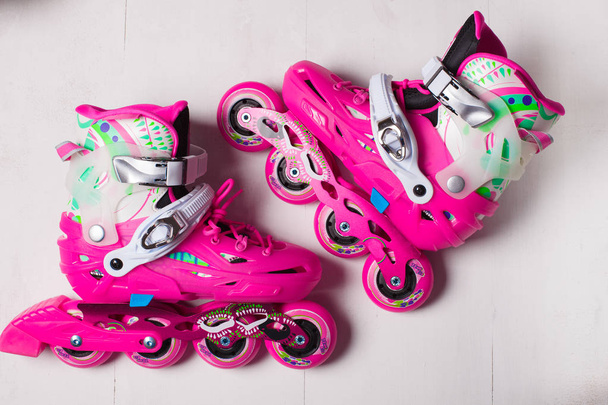 A pair of pink stylish roller skates on a white wooden background - Foto, Imagem