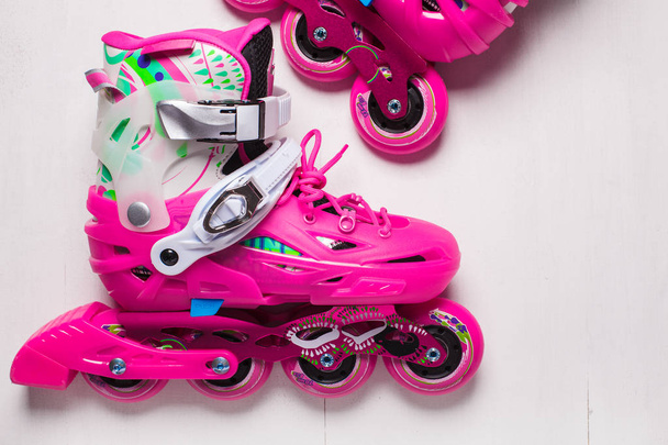 A pair of pink stylish roller skates on a white wooden background - Foto, Imagen