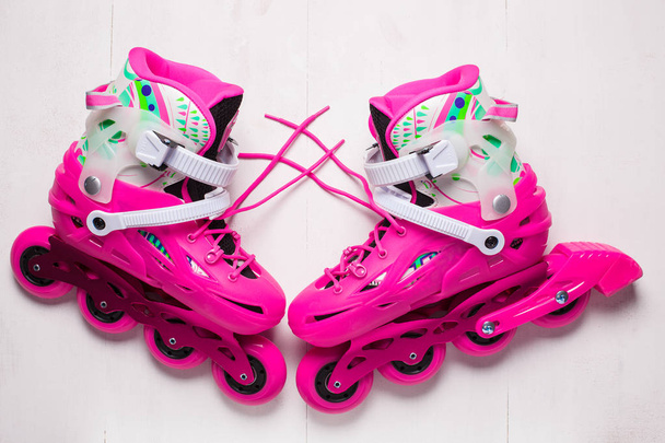 A pair of pink stylish roller skates on a white wooden background - Photo, image