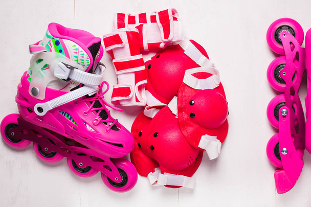 A pair of pink stylish roller skates on a white wooden background - Foto, Imagem