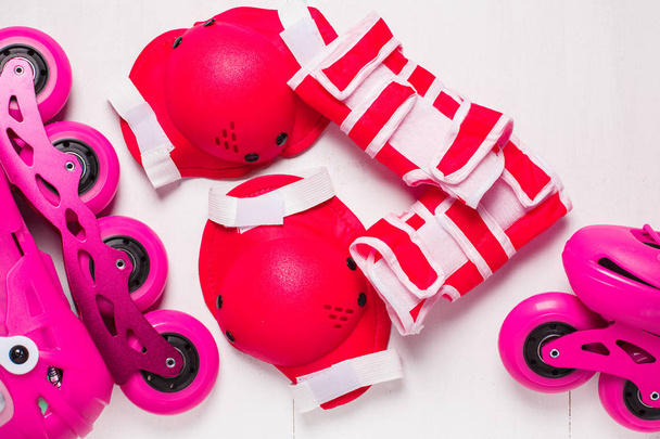 A pair of pink stylish roller skates on a white wooden background - Foto, immagini