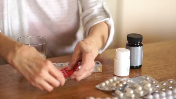 A woman suffering from arthritis takes a large number of pills. Medicine concept, close-up of the hand of a person with arthritis - Imágenes, Vídeo