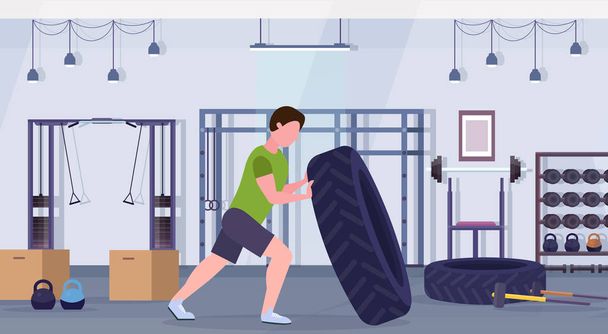 sports man flipping a tire doing hard exercises guy working out in gym crossfit training healthy lifestyle concept modern health club studio interior horizontal - Vektor, Bild
