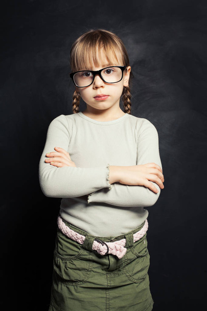 Cute child in glasses thinking against school classroom blackboad - Foto, Bild