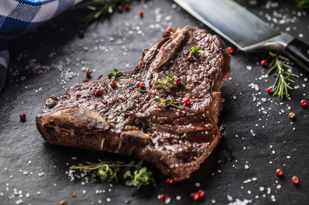 Boeuf T-Bone steak avec sel, poivre et romarin sur plaque d'ardoise
 - Photo, image