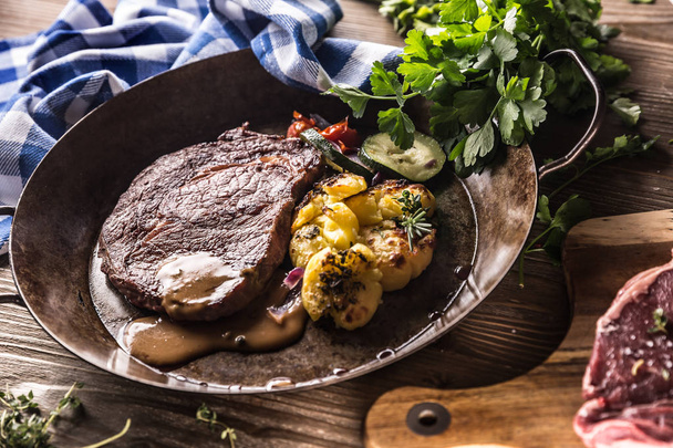 Juicy beef Rib Eye steak roasted potatoes with sauce grilled vegetable salt pepper and herbs in vintage pan - Фото, зображення