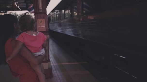 Mutter und Kind stehen am Bahnhof im thailändischen Hin und winken dem abfahrenden Zug zu. Bahnfahren mit einem Kind. Zeitlupe. Retro-Verarbeitung. - Filmmaterial, Video