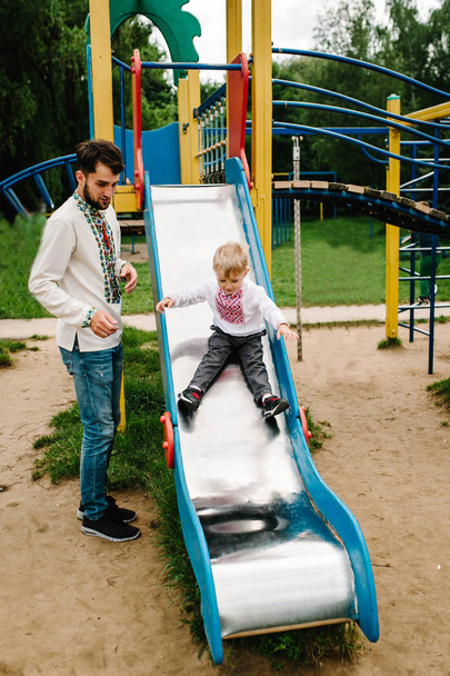 Little boy in embroidered shirt playing on playground in park - Zdjęcie, obraz