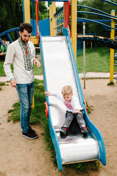 Little boy in embroidered shirt playing on playground in park - Foto, imagen