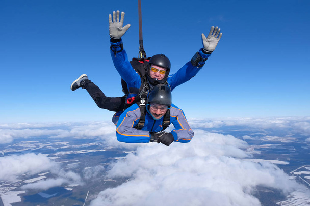 Тандем прыгает с парашютом. Два парня веселятся в голубом небе
. - Фото, изображение
