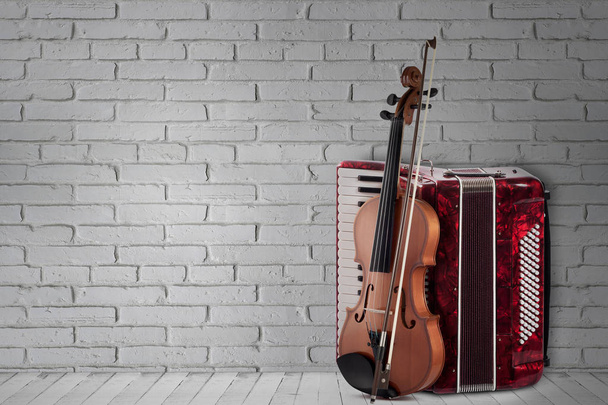 Vintage acordeón rojo y violín sobre fondo de pared de ladrillo
 - Foto, imagen