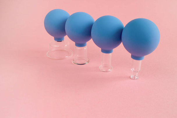 μπλε καλλυντικά βάζα κενού, διαφόρων μεγεθών, κατασκευασμένο από γυαλί και τα λαστιχένια σε ροζ φόντο - Φωτογραφία, εικόνα